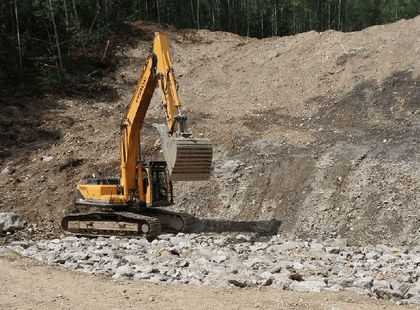 Completed boulder foundation being track-packed by excavator, Mackenzie, BC