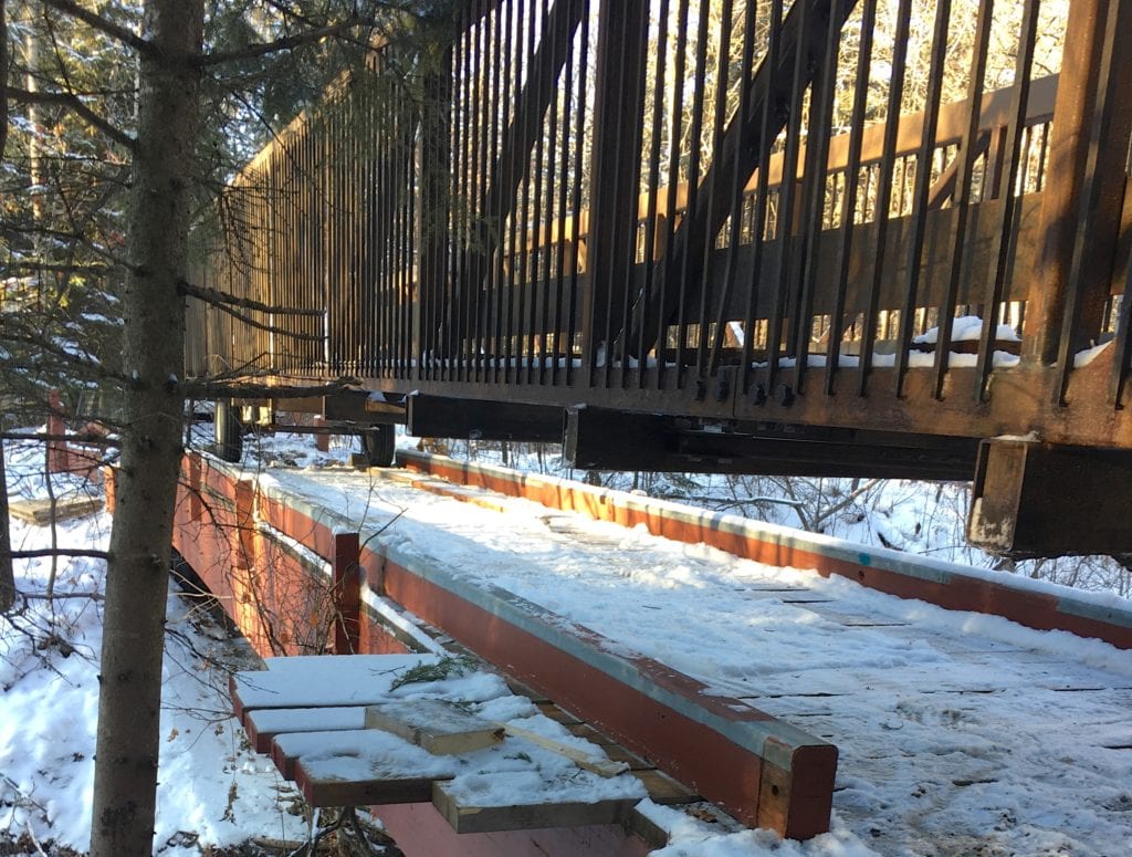 Prefabricated trail bridge rolls across old bridge