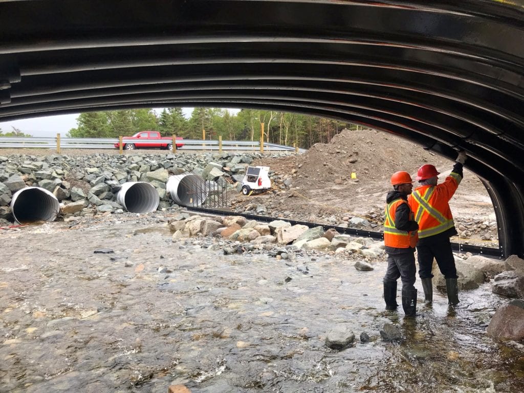 Crew working on box culvert assembly over active streambed