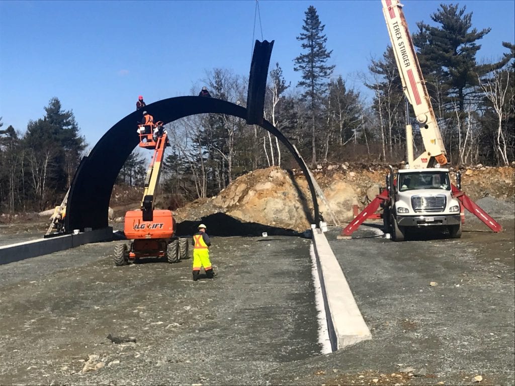 Concrete footing for buried metal bridge highway overpass