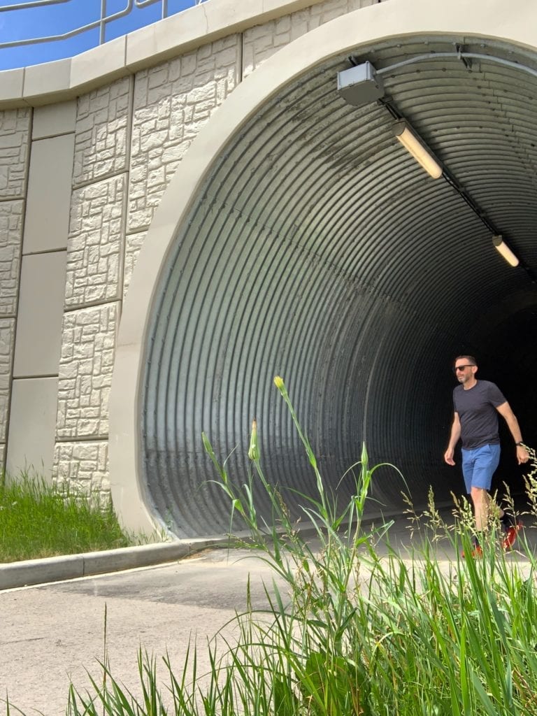 Trail-level view of pedestrian in buried metal tunnel